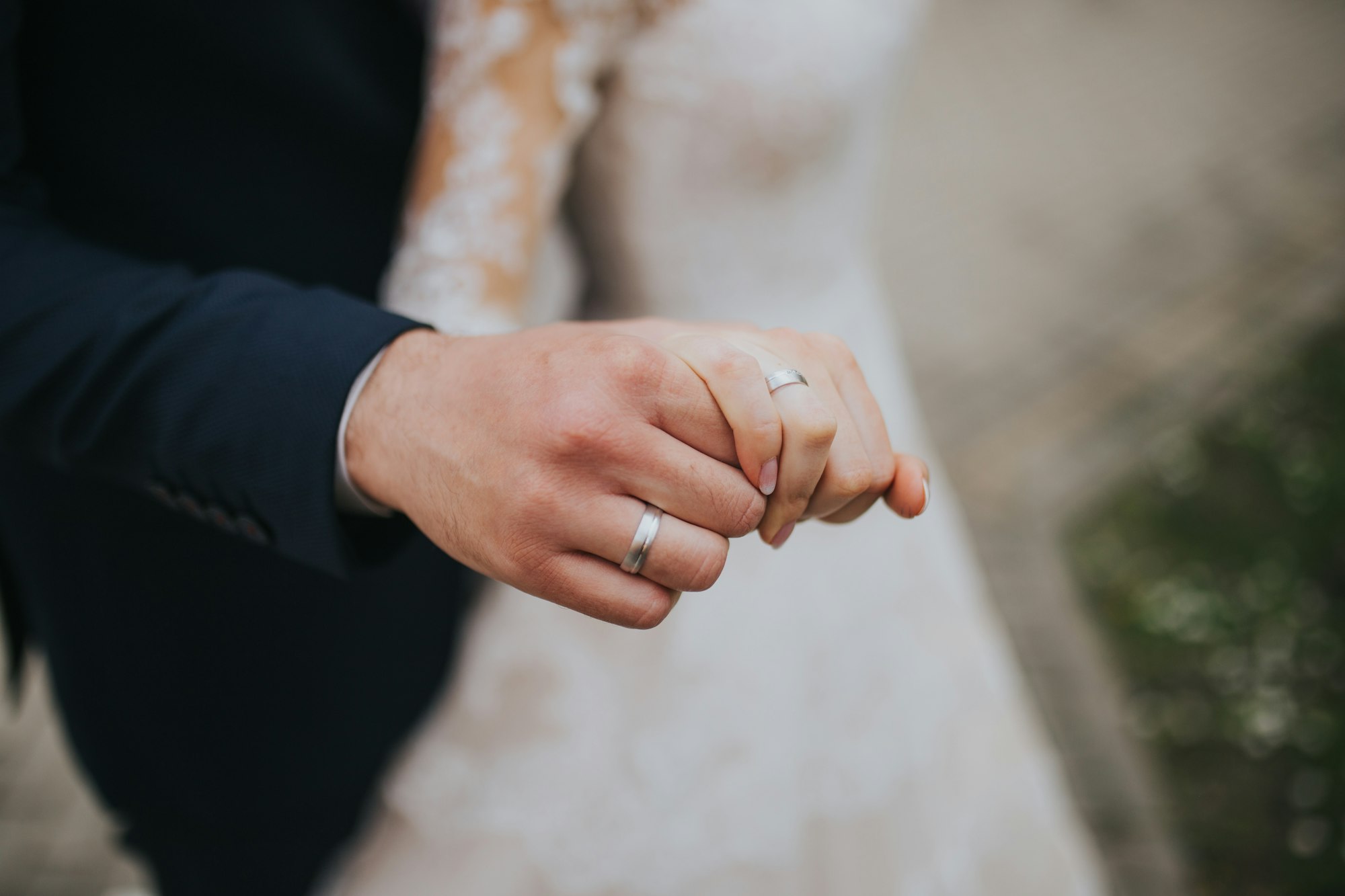 Closeup shot of a couple holding hands with marriage rings on a wedding day